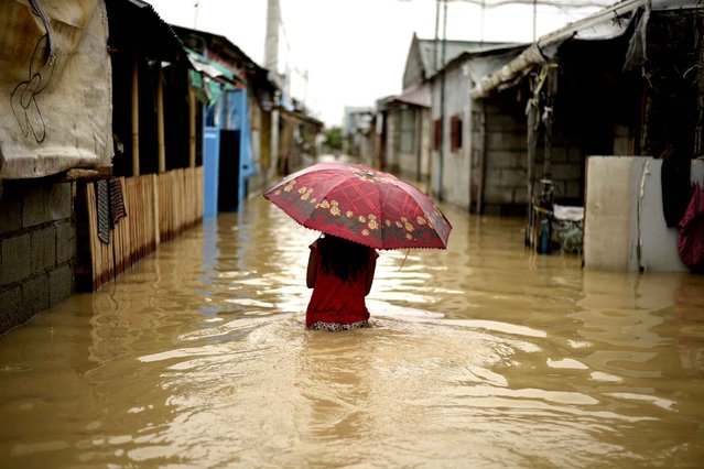 A girl with an umbrella wades through a flooded street in Calumpit, Bulacan, suburban Manila on December 20, 2015. The death toll from two storms which battered the Philippines rose to 45 as several towns remained under water and rain kept falling in northern regions, disaster monitoring officials said. The rain was caused by a cold front, dragged into the country by Typhoon Melor and Tropical Depression Onyok which hit the Philippines in succession last week. (Photo by Noel Celis/AFP Photo)
