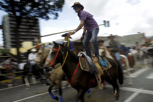 A man performs as he takes part in a traditional horse parade through the streets of San Jose, Costa Rica December 26, 2015. (Photo by Juan Carlos Ulate/Reuters)