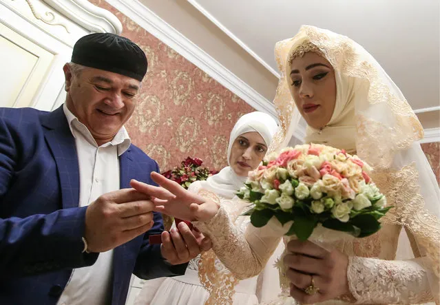 The groom' s uncle puts a ring on the bride' s finger in her room during a traditional Chechen wedding ceremony in Grozny, Chechnya, Russia on November 24, 2016. (Photo by Valery Sharifulin/TASS)