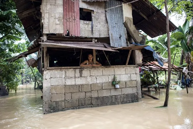 A woman looks out of her home at floodwaters as the Marikina river swelled after continuous rain caused by Tropical Storm Inday (Ampil) in Manila on July 20, 2018. (Photo by Noel Celis/AFP Photo)