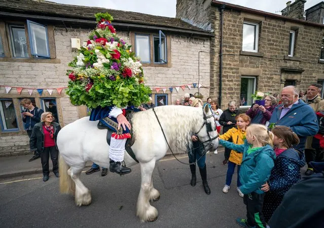 Ceremonial king, Jon Haddock, wears a large flower-covered framework while leading a procession on horseback during Castleton Garland, an ancient tradition that takes place in the village of Castleton, in the Peak District National Park, Derbyshire on Monday, May 30, 2022. (Photo by Danny Lawson/PA Images via Getty Images)