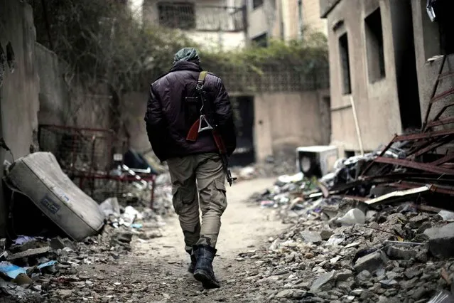 A fighter from the Jaish al-Islam (Islam Army), the foremost rebel group in Damascus province who fiercely opposed to both the regime and the Islamic State group, patrols the front line in Jobar, on the eastern edge of the Syrian capital on January 4, 2016. Jaish al-Islam has fought off both government forces and IS group jihadists in its Eastern Ghouta bastion, east of the capital. (Photo by Amer Almohibany/AFP Photo)