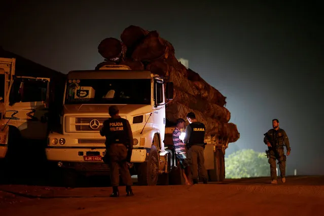 Agents of the Brazilian Institute for the Environment and Renewable Natural Resources, or Ibama, supported by military police, inspect a truck loaded with tree trunks during an operation to combat illegal mining and logging, in the municipality of Peixoto Azevedo, Para State, northern Brazil, November 9, 2016. (Photo by Ueslei Marcelino/Reuters)
