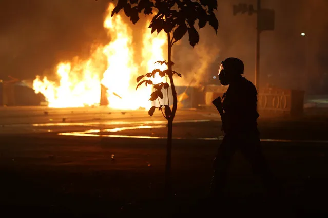 A riot policeman clashing with anti-government demonstrators, is pictured next to burning barricades during a protest against a constitutional amendment, known as PEC 55, that limit public spending, in front of Brazil's National Congress in Brasilia, Brazil, November 29, 2016. (Photo by Adriano Machado/Reuters)