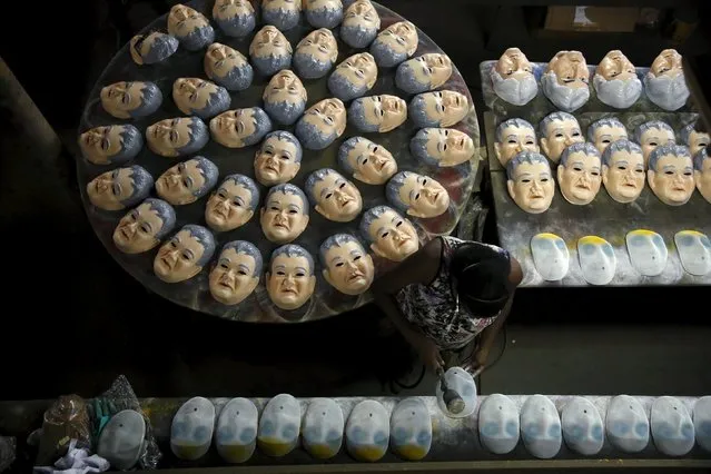 A worker puts the final touches on a carnival mask bearing the likeness of federal police agent Newton Ishii, next to masks of Brazil's Senator Delcidio Amaral, at a costume factory in the suburb of Rio de Janeiro, Brazil, January 11, 2016. The masks are being produced for the upcoming "Brazil Carnival" festival, according to the manufacturer. (Photo by Pilar Olivares/Reuters)