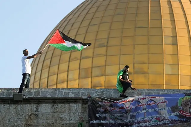 A youth waves a Palestinian flag as the Dome of the Rock is seen in the background, during Eid al-Fitr prayers, which marks the end of the holy fasting month of Ramadan, at the compound that houses al-Aqsa mosque, known to Muslims as Noble Sanctuary and to Jews as Temple Mount, in Jerusalem's Old City, amid Israel-Gaza fighting May 13, 2021. (Photo by Ammar Awad/Reuters)