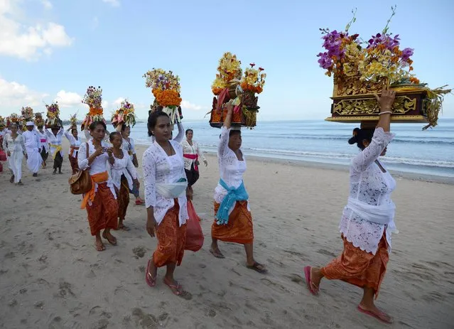 Balinese people carry offerings during the Melasti ceremony prayer at Kuta beach on the island of Bali on March 18, 2015. (Photo by Sonny Tumbelaka/AFP Photo)