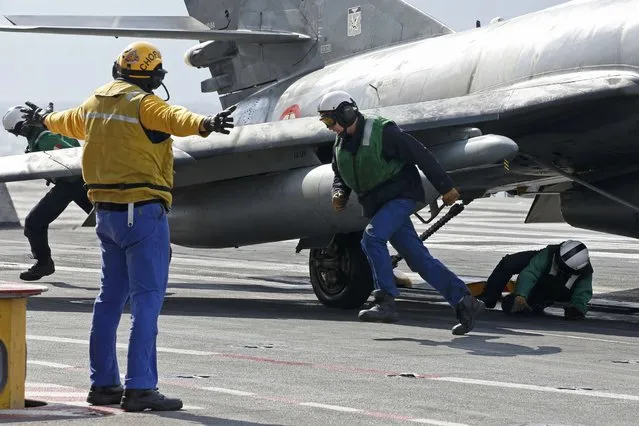 A “Yellow dog” flight deck director signals sailors to quickly get away after they installed a sling on a Super Etendard fighter jet before it will be catapulted aboard France's Charles de Gaulle aircraft carrier on mission in the Gulf, January 29, 2016. (Photo by Philippe Wojazer/Reuters)