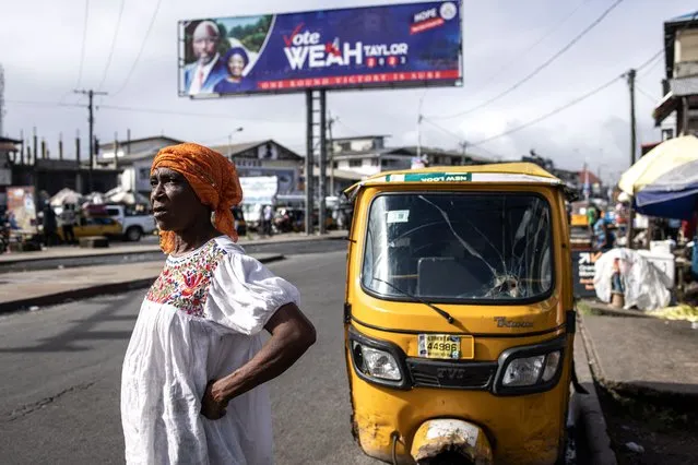 A woman waits for transport under a campaign billboard for the President of Liberia George Weah in Monrovia, on October 4, 2023. Liberia is scheduled to hold general elections on October 10, 2023. (Photo by John Wessels/AFP Photo)