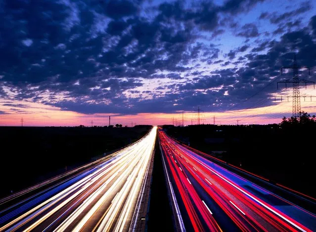 Long exposure picture shows driving cars on the highway just before sunrise near Frankfurt , central Germany, Friday, August 17, 2018. (Photo by Michael Probst/AP Photo)