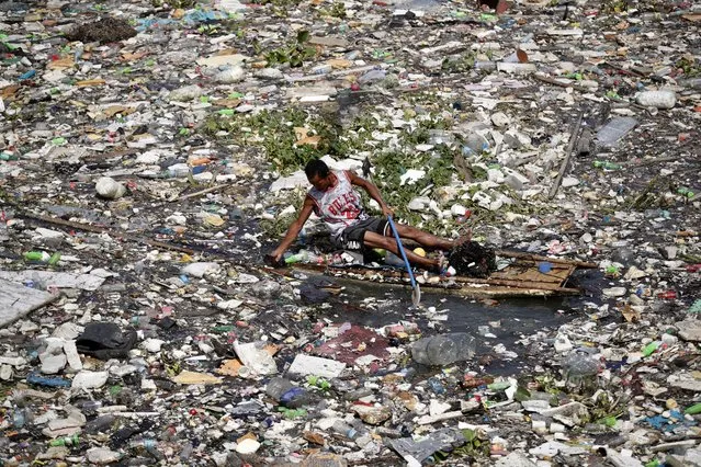 A villager riding on a makeshift raft collects washed up materials at a fishing village in Paranaque city, Metro Manila, Philippines, 28 August 2023. The state weather bureau warned on 28 August, a new typhoon may enter the country with an international name ‘Haikui’ this week as Typhoon Saola dumped rain that brought floods. Saola effect had brought villagers to fled their homes as floods swept through villages in northeastern Philippines. (Photo by Francis R. Malasig/EPA)