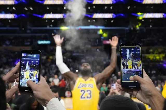 Los Angeles Lakers forward LeBron James tosses powder in the air as fans take video prior to an NBA basketball game against the Los Angeles Clippers Wednesday, November 1, 2023, in Los Angeles. (Photo by Mark J. Terrill/AP Photo)