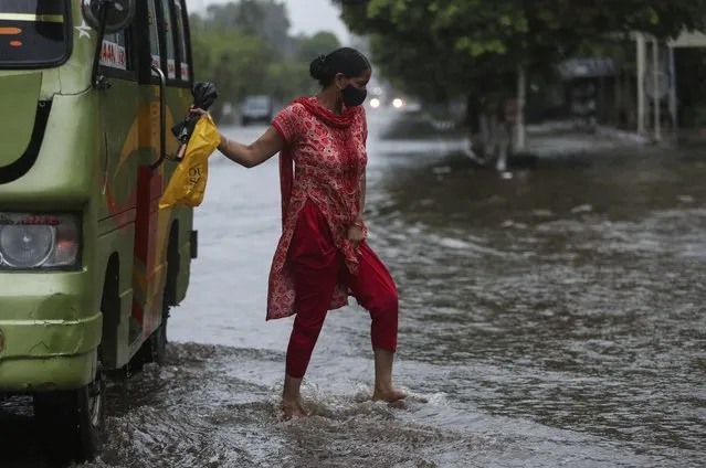 A woman alights from a bus at a flooded street during monsoon rains Jammu, India, Monday, July 12, 2021. (Photo by Channi Anand/AP Photo)