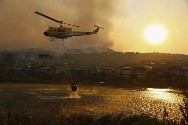 Firefighting helicopters battle a vegetation fire fanned by gale force winds raging in the Helderberg mountains around Somerset West, South Africa, 04 January 2017. Over 120 firefighters, three helicopters and a water bombing aircraft have been battling the fire, fanned by winds, around in the Somerset West and Stellenbosch areas. The fire broke out early 03 January, several properties in the area have been evacuated. The cause of the fire is yet unknown. (Photo by Nic Bothma/EPA)