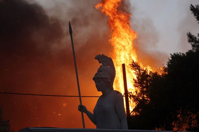 A statue of goddess Athena is seen as wildfire burns at Varympompi suburb north of Athens, Greece, August 3, 2021. (Photo by Giorgos Moutafis/Reuters)