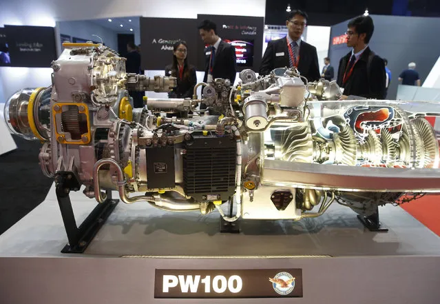 Visitors look at a Pratt and Whitney PW100 engine model at their booth at the Singapore Airshow at Changi Exhibition Center February 18, 2016. (Photo by Edgar Su/Reuters)