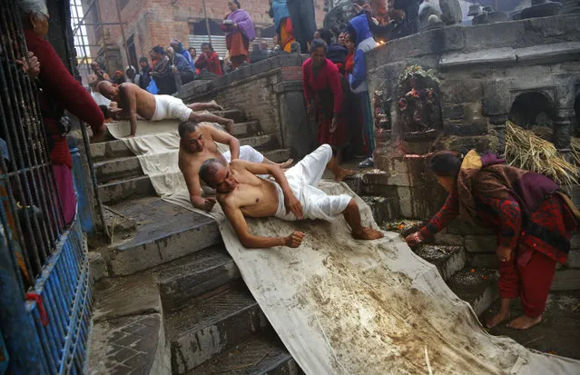 In this Thursday, January 24, 2019, file photo, Nepalese Hindu devotees roll on the ground as part of a ritual during the Madhav Narayan festival in Bhaktapur, Nepal. During this festival, devotees recite holy scriptures dedicated to Hindu goddess Swasthani and Lord Shiva. Unmarried women pray for a good husband while those married pray for the longevity of their husbands by observing a month-long fast. (Photo by Niranjan Shrestha/AP Photo)