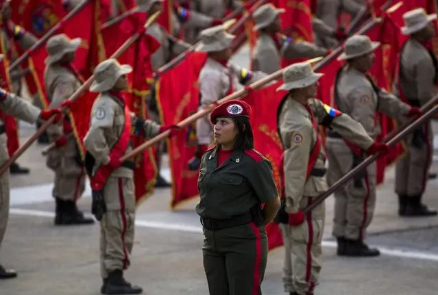 Militia members stand at attention during a ceremony in Caracas April 13, 2015. Supporters of late Venezuelan President Hugo Chavez commemorated 13 years of his return to power after a brief coup that ousted him for two days in 2002. April 13 is now celebrated in the country as the day of the militia. (Photo by Marco Bello/Reuters)