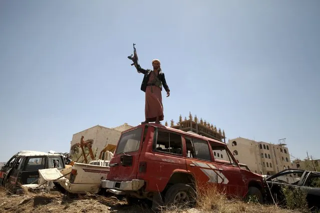 A follower of the Houthi group raises his weapon as he stands on a vehicle on a damaged street, caused by an April 20 air strike that hit a nearby army weapons depot, in Sanaa April 21, 2015. (Photo by Mohamed al-Sayaghi/Reuters)