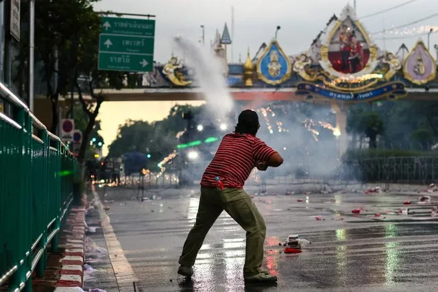 An anti-government protester launches a firework at the police during a demonstration in Bangkok on September 27, 2021, as activists call for the resignation of Thailand's Prime Minister Prayut Chan-O-Cha over the government's handling of the Covid-19 coronavirus crisis. (Photo by Jack Taylor/AFP Photo)