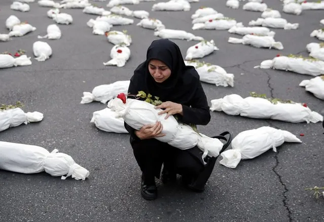 An Iranian woman mourns over a mock dead body, displayed in tribute to the children who died amid the Israel-Hamas conflict, during an event in solidarity with the Palestinian people, held at the Palestine square, in Tehran, Iran, 13 November 2023. Thousands of Israelis and Palestinians have died since the militant group Hamas launched an unprecedented attack on Israel from the Gaza Strip on 07 October, and the Israeli strikes on the Palestinian enclave which followed it. (Photo by Abedin Taherkenareh/EPA/EFE)