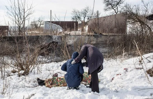 Nadiya Volkova, 24, is comforted by her mother-in-law Galina Nikolaevna as she grieves over the body of her mother Katya Volkova, 60, who was killed by shelling at around 7:30am as she walked to the store on February 1, 2017 in Avdiivka, Ukraine. (Photo by Brendan Hoffman/Getty Images)