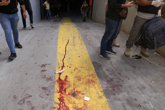 Supporters of a Shiite group allied with Hezbollah stand next to blood from an injured comrade during armed clashes that erupted during a protest in the southern Beirut suburb of Dahiyeh, Lebanon, Thursday, October 14, 2021. (Photo by Hassan Ammar/AP Photo)