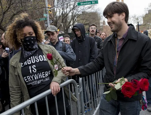 A man passes out roses to demonstrators calling for social, economic and racial justice march in New York May 1, 2015. (Photo by Brendan McDermid/Reuters)