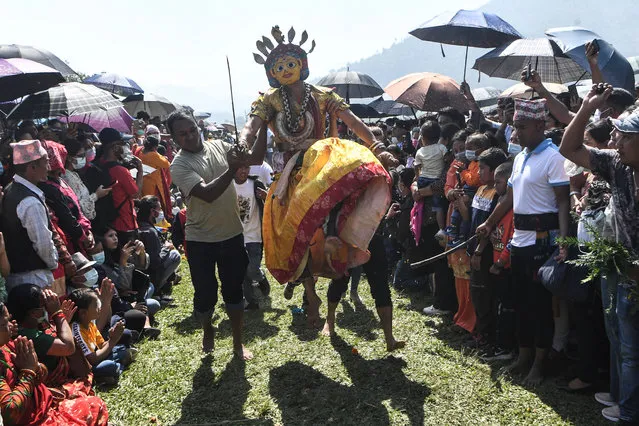 A Hindu devotee dressed as a deity (C) participates during celebrations for the Shikali Jatra festival at Khokana village, on the outskirts of Kathmandu on October 12, 2021. (Photo by Prakash Mathema/AFP Photo)