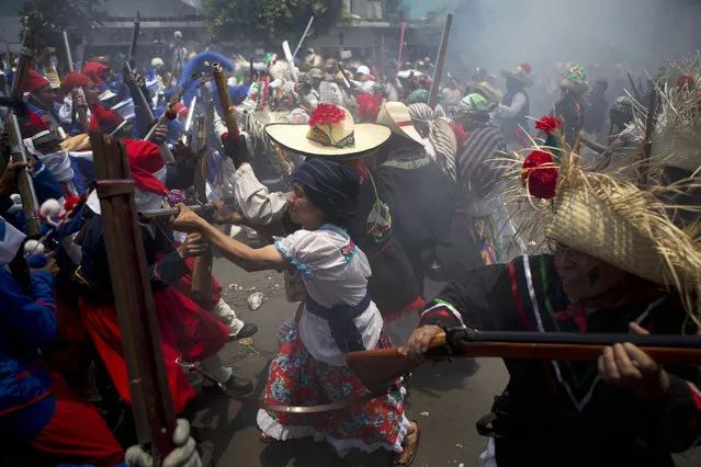 Local residents dressed as Zacapoaxtla Indians, right, and French soldiers, left, clash during a reenactment of the battle of Puebla, during Cinco de Mayo celebrations in the Penon de los Banos neighborhood of Mexico City, Tuesday, May 5, 2015. (Photo by Rebecca Blackwell/AP Photo)