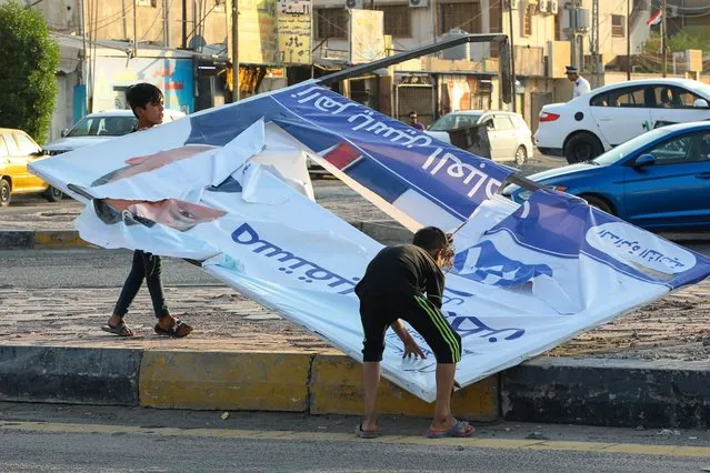Demonstrators tear down electoral posters for the early parliamentary elections during anti-government protests in Najaf, Iraq, Friday, October 1, 2021. The candidates know convincing Iraq's disillusioned youth to trust in an electoral process tainted with a history of tampering and fraud is their best chance to win seats. (Photo by Anmar Khalil/AP Photo)