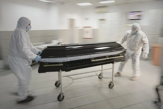 Funeral house employees drag a coffin on a trolley as they arrive at the University Emergency Hospital morgue to take a COVID-19 victim for burial, in Bucharest, Romania, Monday, November 8, 2021. Hundreds of people have been dying daily for the past two months in Romania which has been among the hardest-hit in the current virus onslaught raging through Central and Eastern European nations where far fewer people have been inoculated than in Western Europe. (Photo by Vadim Ghirda/AP Photo)