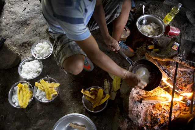 In this March 13, 2015 photo, Donato fries an egg over an open fire to add to his breakfast of rice and plantain, before starting his work day of weeding coca fields, in La Mar, province of Ayacucho, Peru. Roughly one third of the 305 metric tons of cocaine that the U.S. government estimates Peru produces each year travels by foot by way of cocaine backpackers or mochileros, as they are known locally. (Photo by Rodrigo Abd/AP Photo)