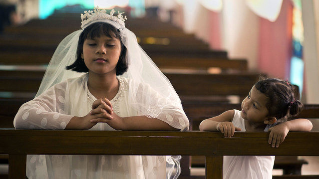 An Indian Christian girl watches another praying during Easter mass at a church in Gauhati, India, Sunday, March 27, 2016. Christians around the world are celebrating Easter commemorating the day when according to Christian tradition Jesus was resurrected in Jerusalem two millennia ago. (Photo by Anupam Nath/AP Photo)