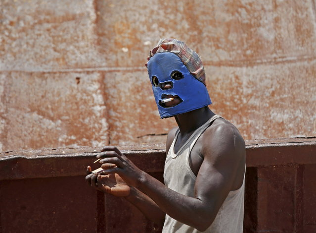 A masked protestor smokes during a protest against President Pierre Nkurunziza's decision to run for a third term in Bujumbura, Burundi, May 11. 2015. (Photo by Goran Tomasevic/Reuters)