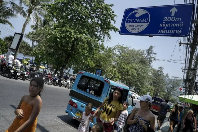 Tourists walk past an evacuation sign near Patong beach in Phuket, Thailand, March 19, 2016. (Photo by Athit Perawongmetha/Reuters)