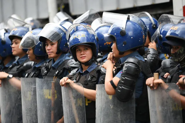 Policewomen in riot gear wait for women activists during a protest to mark International Women's Day in Manila on March 8, 2024. (Photo by Ted Aljibe/AFP Photo)