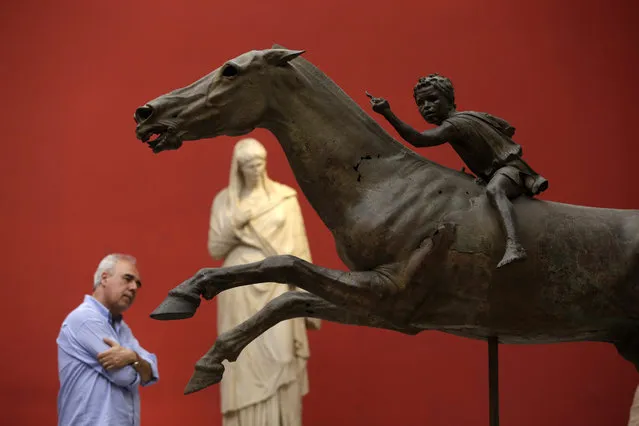 A man looks at the 140 B.C. bronze statue of a young jockey riding a horse during the International Day Museum with free entrance for the visitors, at the Archeological museum in Athens on Monday, May 18, 2015. Greece's cash-strapped government signaled Monday it needs a deal with bailout lenders by the end of the month to keep up loan repayments though the summer, as renewed concern rattled markets and saw borrowing rates shoot up. (Photo by Thanassis Stavrakis/AP Photo)