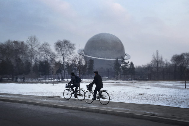 North Koreans cycle past a planetarium at the Three Revolutions Exhibition Hall on Tuesday, February 23, 2016, in Pyongyang, North Korea. (Photo by Wong Maye-E/AP Photo)