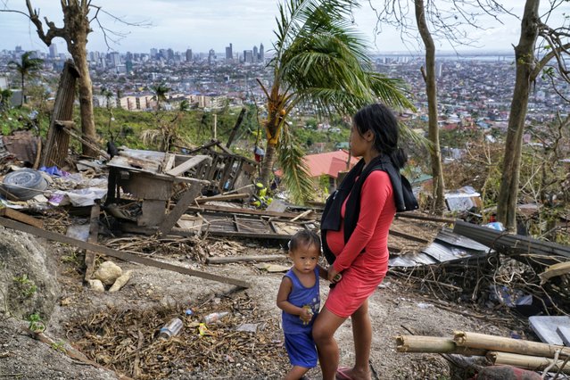 Alona Nacua, right, stands beside her son as she looks at their damaged house due to Typhoon Rai in Cebu city, central Philippines on Christmas Day, Saturday, December 25, 2021. Nacua said she and her husband managed to receive rice and four small cans of sardines and corned beef so they could feed their family Saturday. “It's the saddest Christmas for me, seeing my children suffer this way on this day”, added Nacua, who is pregnant with her fourth child. (Photo by Jay Labra/AP Photo)