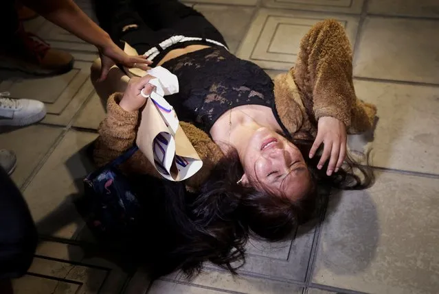 A woman is helped as she reacts on the floor amid anti-government protests after Peru's former President Pedro Castillo was ousted, in Lima, Peru on January 23, 2023. (Photo by Pilar Olivares/Reuters)