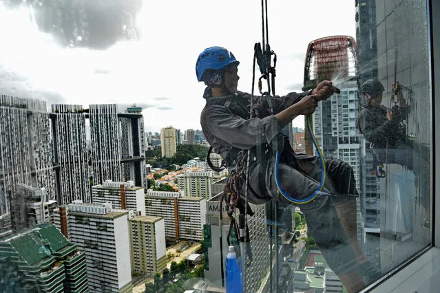 Workers clean glass windows of a highrise building in Singapore on June 14, 2019. (Photo by Roslan Rahman/AFP Photo)