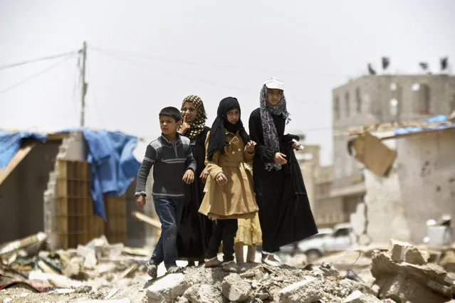 A boy and his sisters watch graffiti artists spray on a wall, commemorating the victims who were killed in Saudi-led coalition airstrikes in Sanaa, Yemen, Monday, May 18, 2015. (Photo by Hani Mohammed/AP Photo)