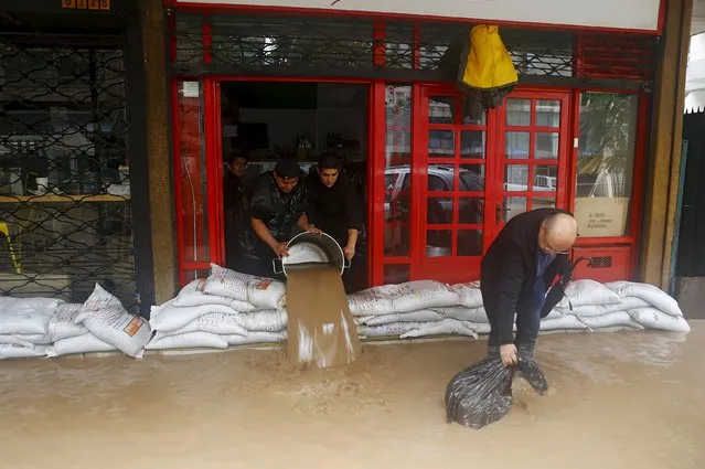 Workers remove water from a store in a flooded street in Santiago, April 17, 2016. (Photo by Ivan Alvarado/Reuters)