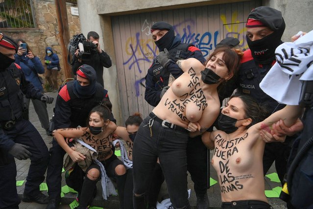Femen activists with their bare chests reading “Fascists out of ballot boxes” are held back by Catalan regional police forces Mossos d'Esquadra as they protest against far-right Vox party candidates in Barcelona during regional elections in Catalonia on February 14, 2021. Catalonia is voting in an election overshadowed by the pandemic which Madrid hopes will unseat the region's ruling separatists more than three years after a failed bid to break away from Spain. (Photo by Lluis Gene/AFP Photo/Profimedia)