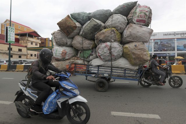 A woman, right, transports huge bags of recyclables on a street, in downtown Phnom Penh, Cambodia, Monday, May 24, 2021. (Photo by Heng Sinith/AP Photo)