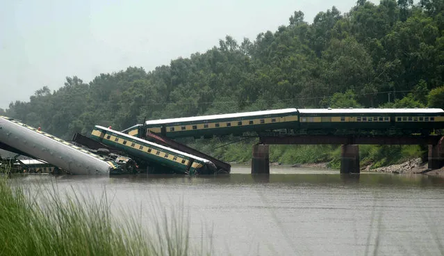 Cars of a passenger train fall after a bridge collapse led a train into a canal in Wazirabad, near Lahore, Pakistan Friday, July 3, 2015. Pakistan's military said Friday the death toll from an accident to a special train that plunged into a canal because of a bridge collapse has risen. Divers were searching for more bodies. (Photo by Rameez Khan/AP Photo)