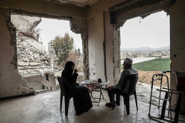 Syrian Umm Mohammed, and her husband drink coffee at their destroyed home in the rebel- held town of Douma, on the outskirts of the capital Damascus, on March 23, 2017. Um Mohammed, who is originally from Aleppo, lives with her husband who due to an air strike injury lost the ability to walk. She farms chicken as a source of food and income. (Photo by Sameer Al- Doumy/AFP Photo)