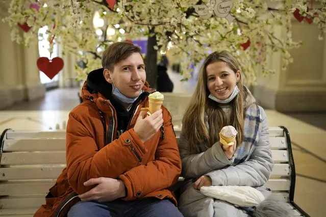 A young couple eat ice cream in the GUM department store in Moscow, Russia, Monday, February 14, 2022. (Photo by Alexander Zemlianichenko/AP Photo)