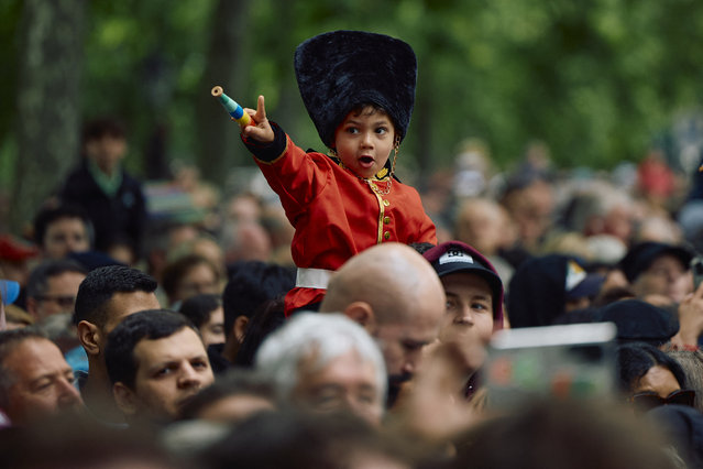 A young member of the public dressed as Grenadier guard sits on the shoulders of a relative during the King's Birthday Parade “Trooping the Colour” in London on June 15, 2024. (Photo by Benjamin Cremel/AFP Photo)